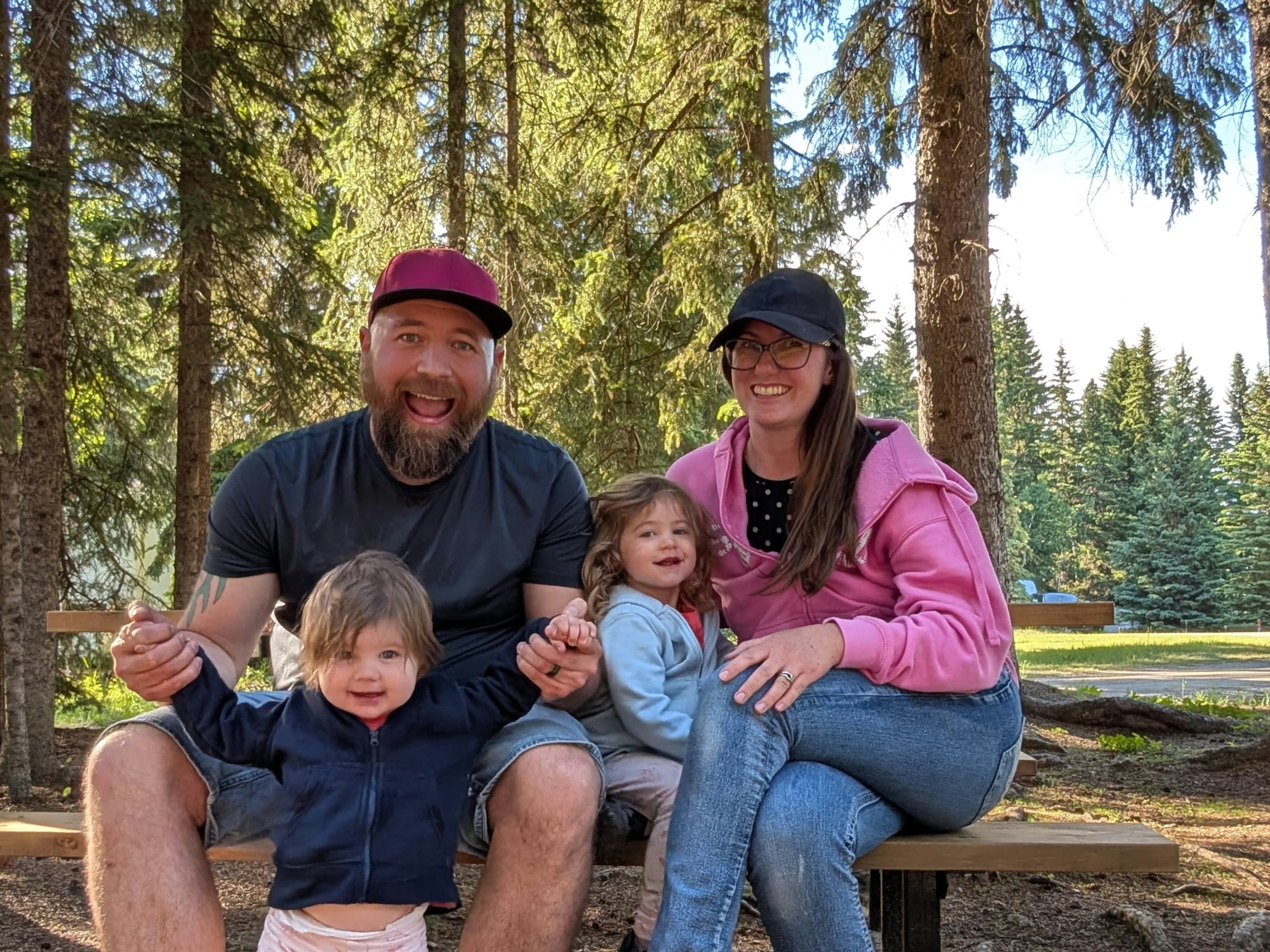 TJ Schmidt with his wife and two daughters outdoors